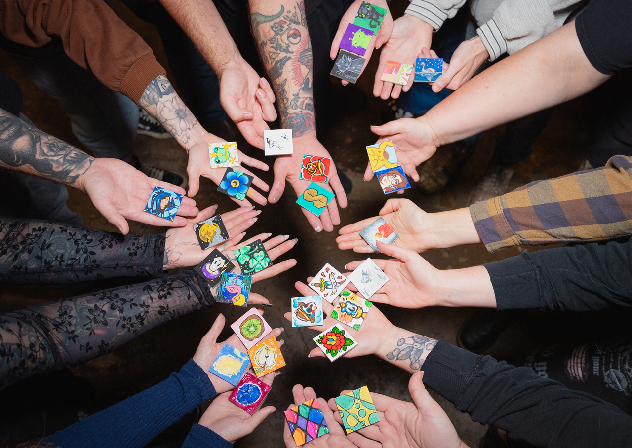 Hands holding colorful miniature artworks