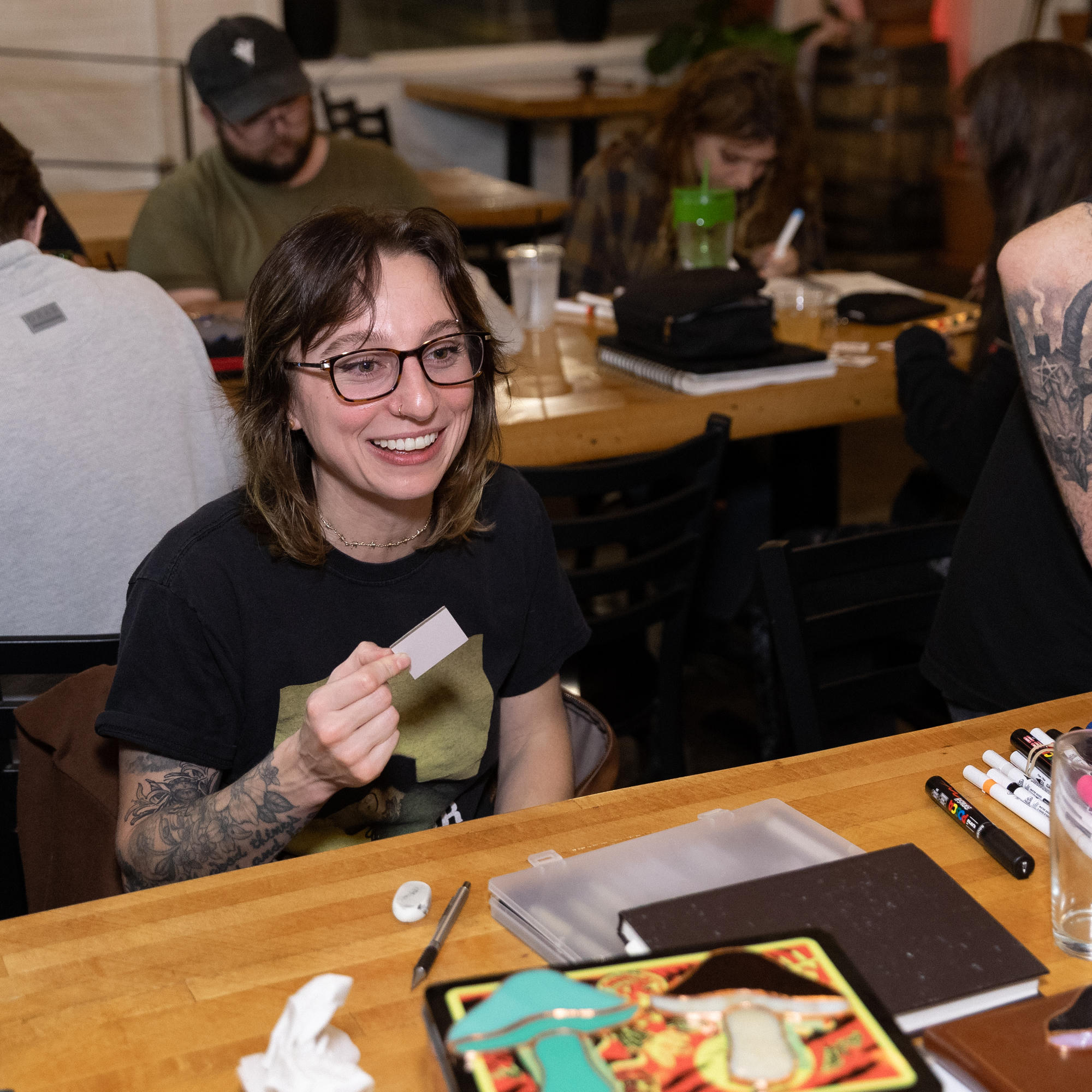 Smiling Art Club participant holding a miniature canvas at the table