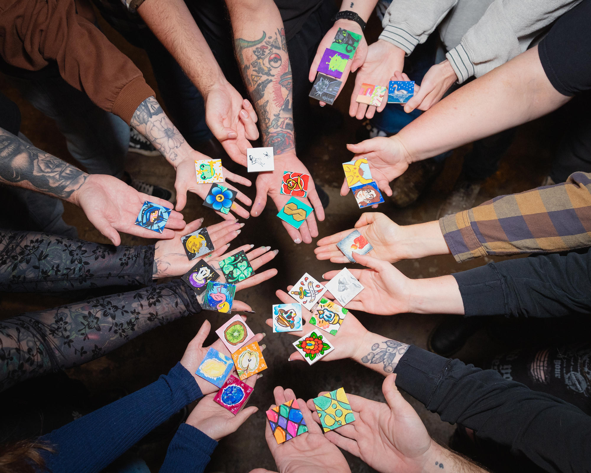 Art Club participants holding their colorful finished miniature canvases together