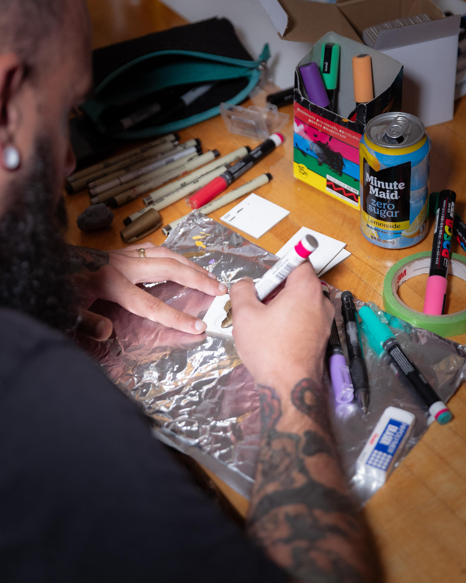 Close-up of hands adding details to a miniature canvas with a paint marker